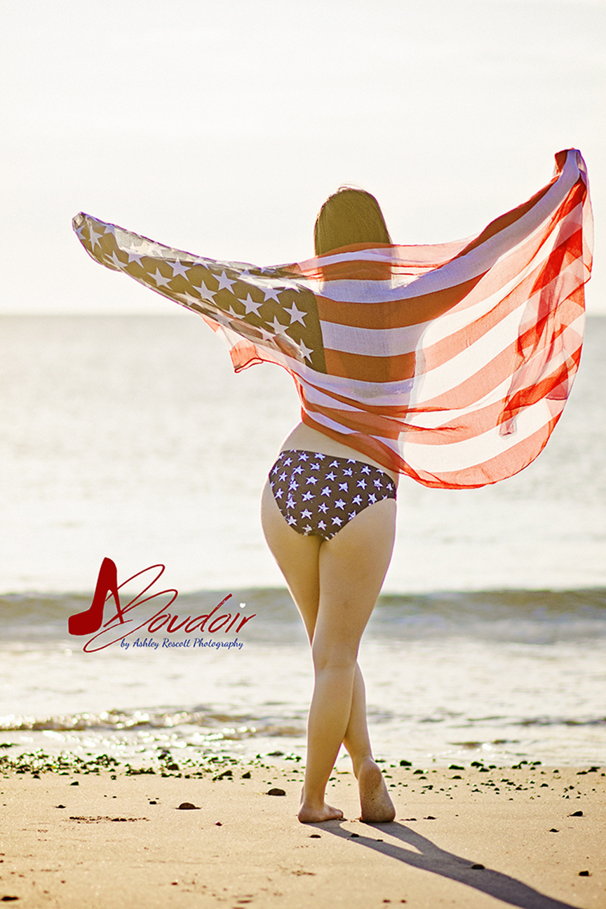 silhouette of girl through american flag on beach