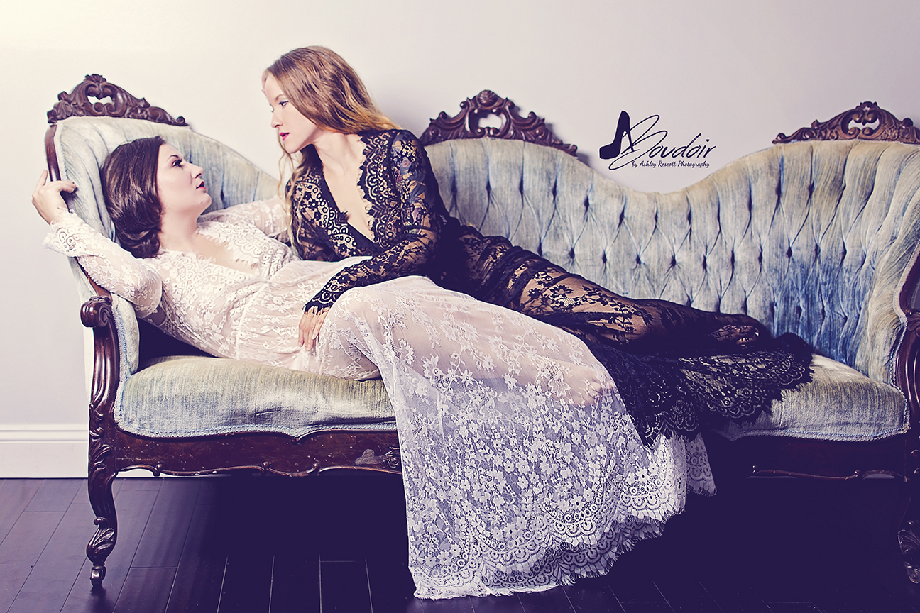 two women reclining on couch in lace dresses