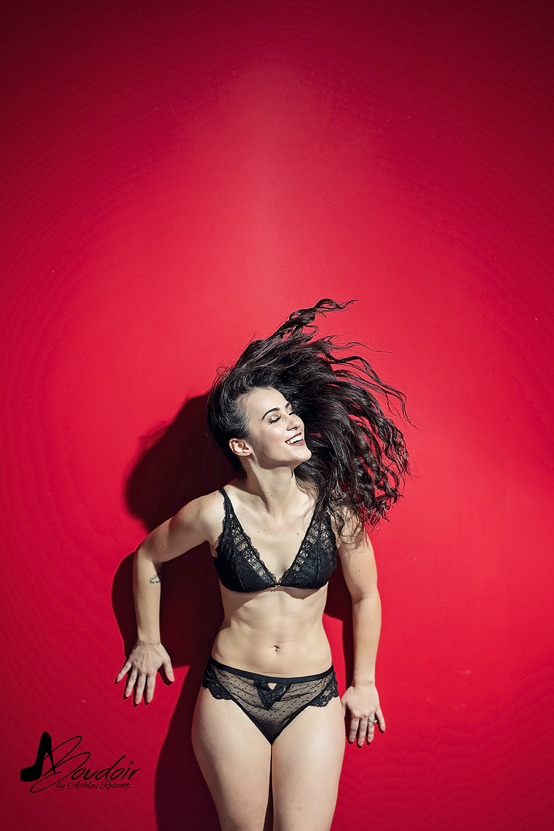 Woman in underwear flipping her brunette hair against a red wall. Hair flip.