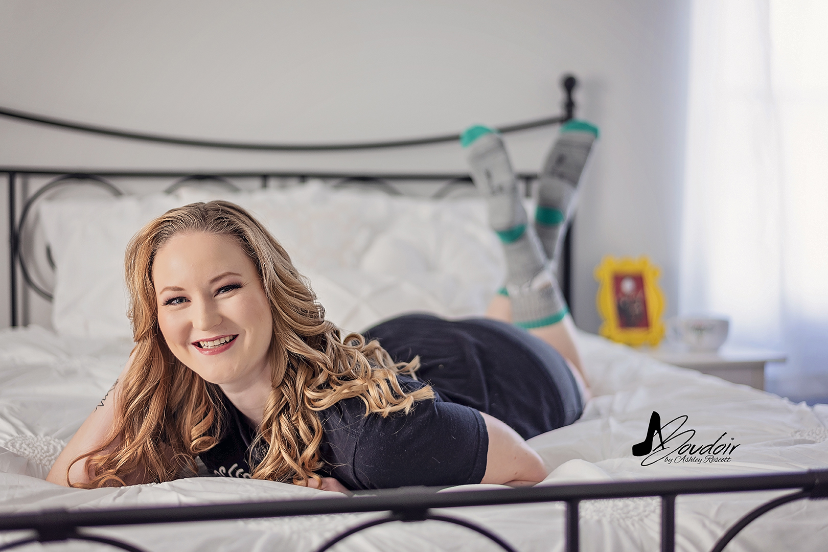 Woman lying in bed in t shirt and socks and smiling