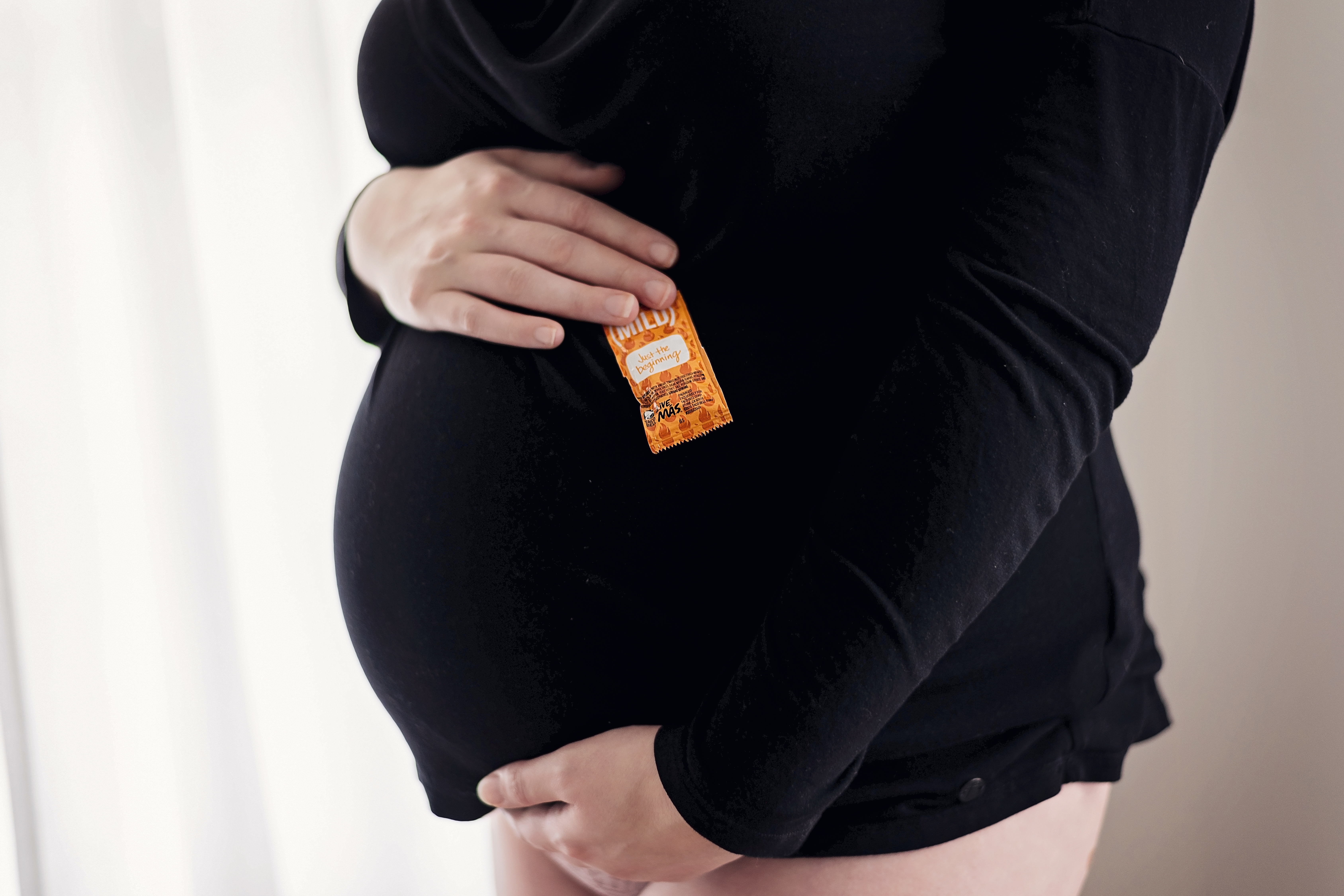 woman holding sauce packet on her baby belly
