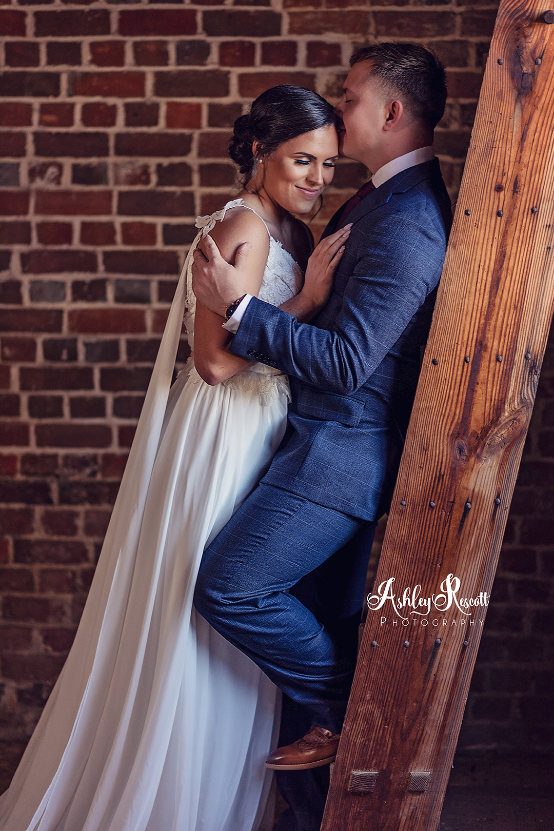 groom leaning against ladder and holding bride