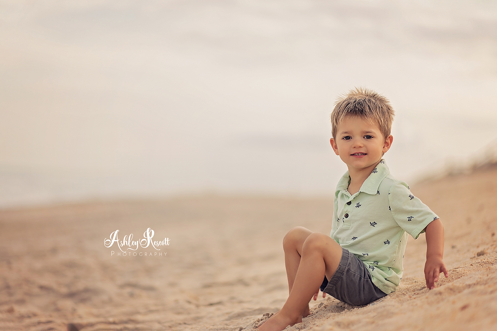 little boy sitting in sand on beach