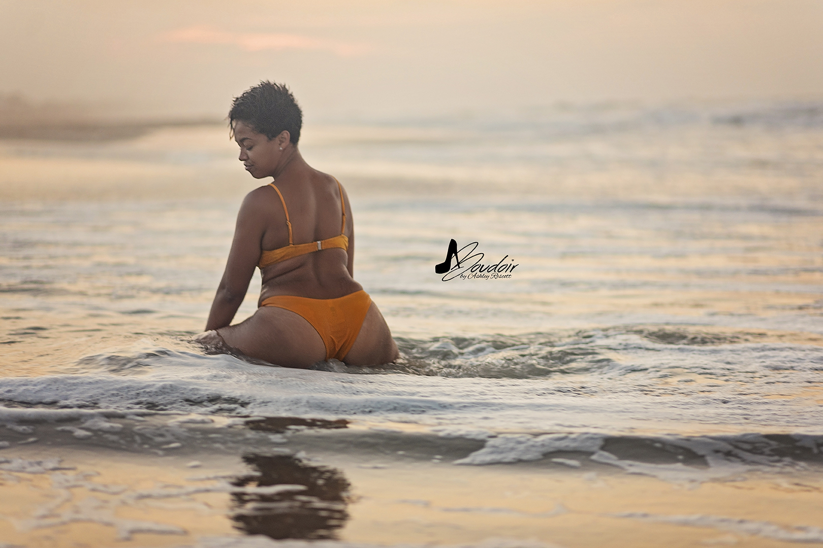 woman sitting in water on beach